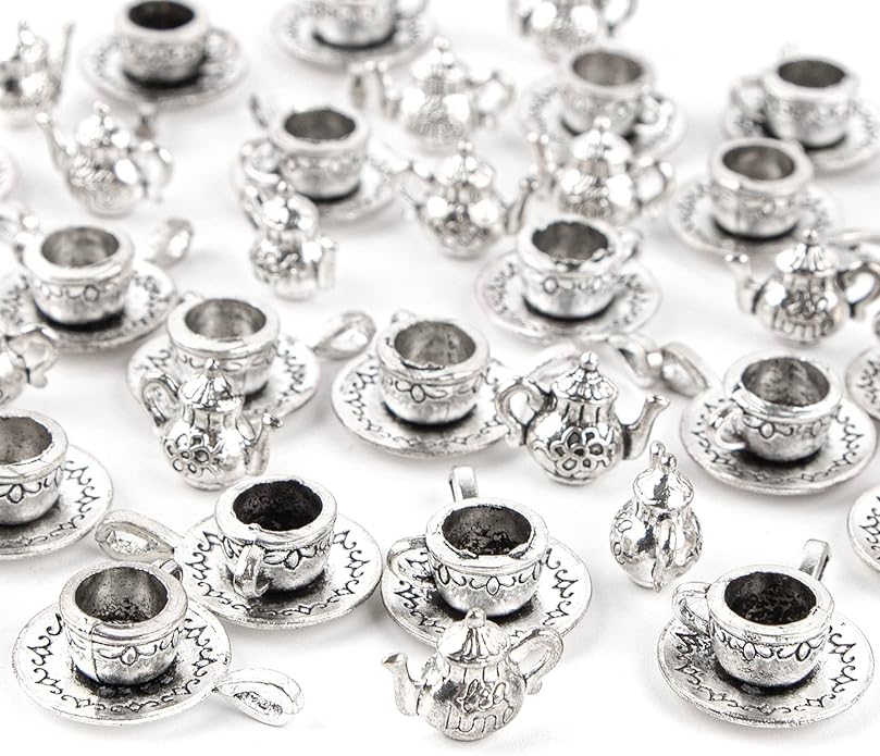 Small silver tea sets scattered on a white surface, featuring teapots, cups, and saucers with decorative patterns.