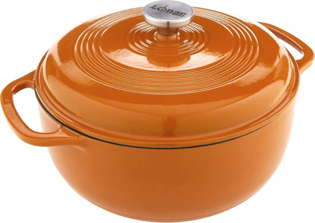An orange enameled cast iron Dutch oven with a lid and two handles, featuring the brand name "Lodge" on the lid knob—perfect for baking bread after learning how to make a sourdough starter.