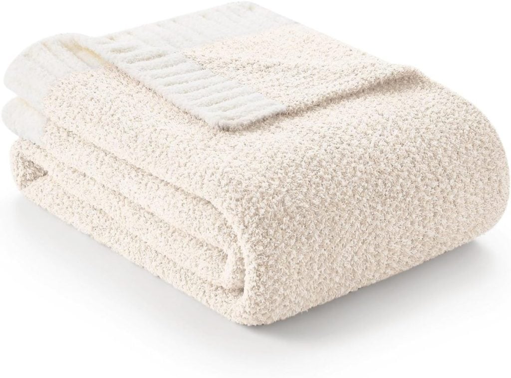 Folded beige towel with a textured surface, placed on a white background.