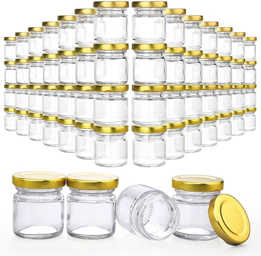 Array of small clear glass jars with gold lids, neatly arranged in rows, with a few jars displayed in the foreground.