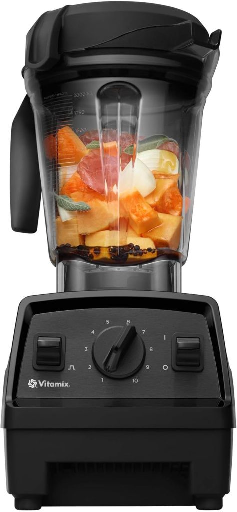 A Vitamix blender, available on Amazon Prime, is filled with vibrant fruits, ready for blending. The control panel features a user-friendly dial and switches for seamless operation.