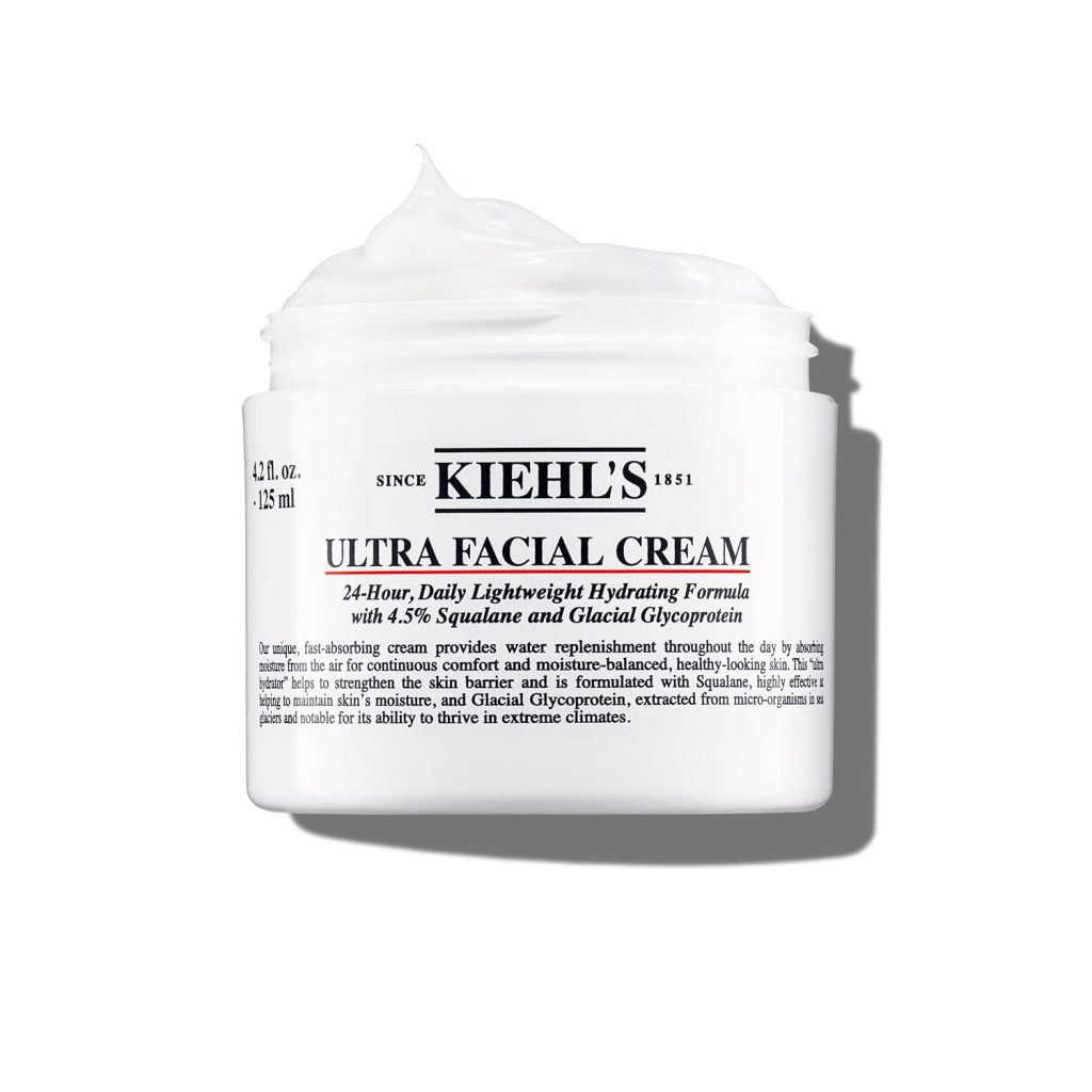 A jar of Kiehl's Ultra Facial Cream with a white lid and text about squalane and glacial glycoprotein for hydration, available on Amazon Prime. The cream is white and fluffy in appearance.