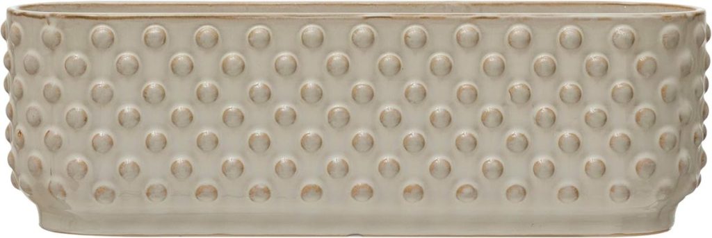 Oval, beige ceramic planter with a raised dot pattern covering the exterior surface—perfect for brightening up your space or serving pie for breakfast with a creative twist.