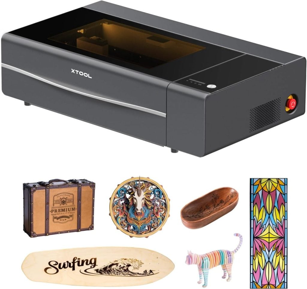 A sleek black-cased laser engraving machine showcases its versatility with engraved items: a suitcase, unicorn plaque, wooden bowl, stained glass, surfboard, and striped cat figure. Available now with the convenience of Amazon Prime for swift delivery.