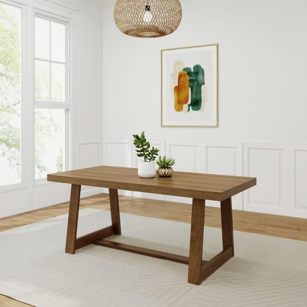 A minimalist dining room features a wooden table, two small potted plants, an abstract painting on the wall, and a woven pendant light. Large windows provide natural light.