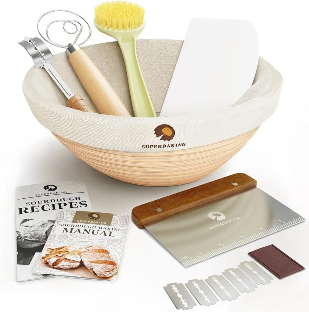 Baking set with a bowl containing a whisk, brush, and spatula, alongside recipe booklets, a dough scraper, and razor blades.