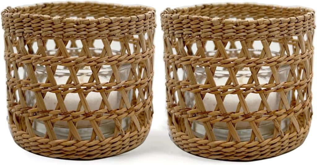 Two glass candles are placed in woven rattan holders, displayed side by side.