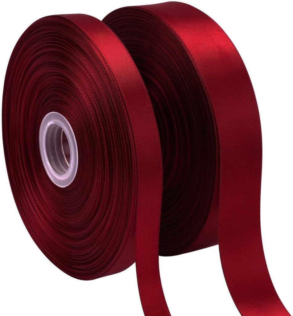 Two rolls of dark red satin ribbon, each with a clear central spool, placed side by side, perfect for sparking ideas for gift wrapping.