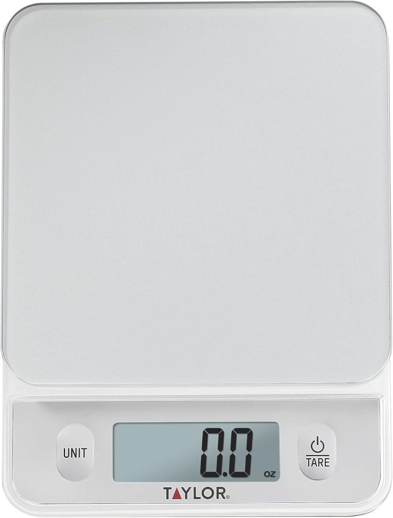 Digital kitchen scale with a glass surface, displaying "0.0 oz" on the LCD screen. Features "UNIT" and "TARE" buttons.