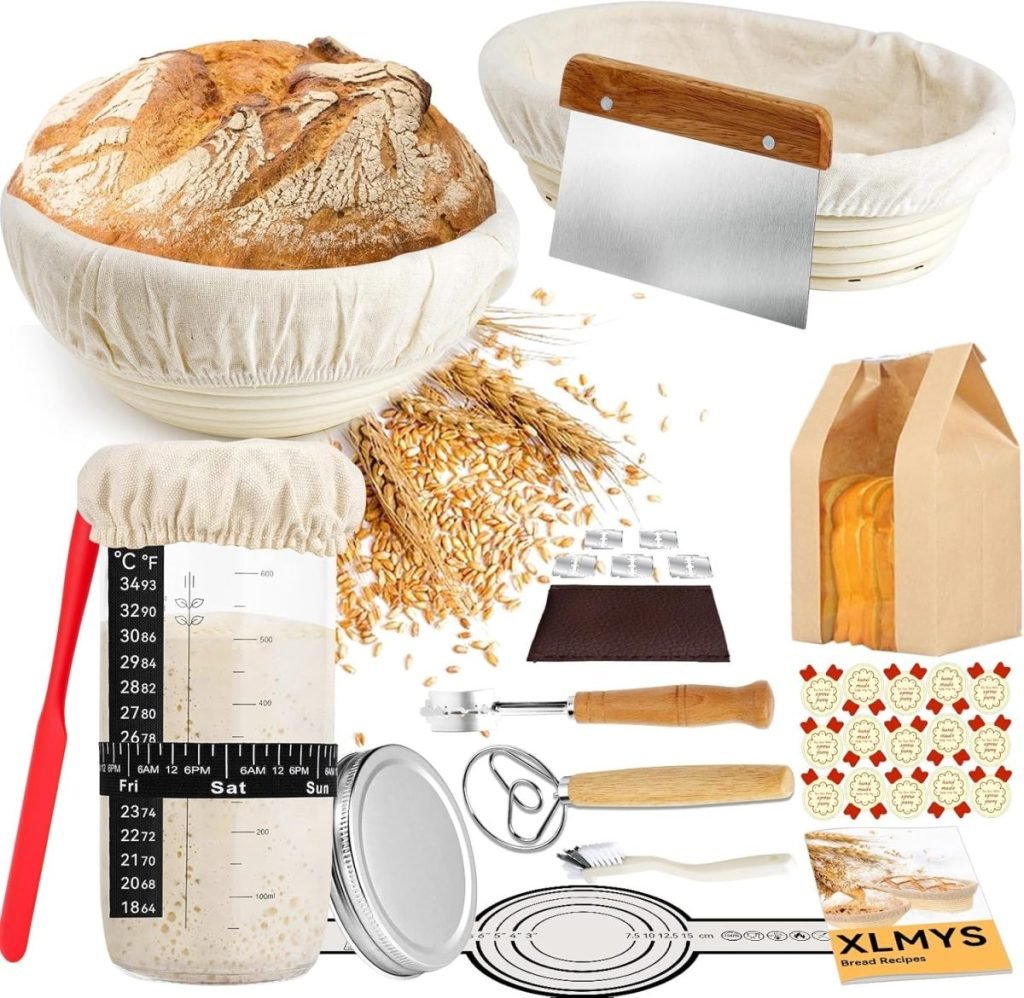 A bread-making kit including a sourdough proofing basket, loaf of bread, dough scraper, measuring jar, whisk, bag of wheat, and other baking tools.