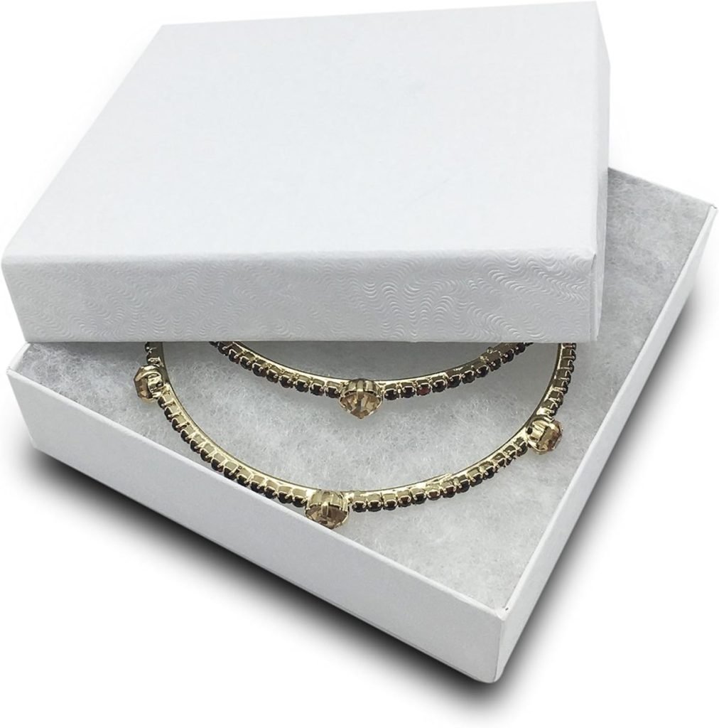 Gold necklace with decorative elements in a white open jewelry box.