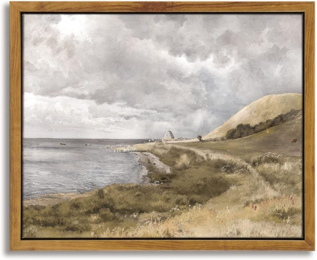 A framed painting depicts a coastal landscape with a cloudy sky, calm sea, and distant hills.