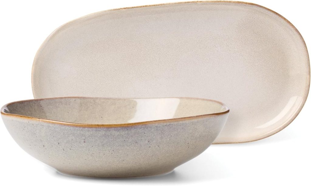 A shallow, oval-shaped beige bowl—perfect for serving fettuccini—is placed in front of a matching beige oval serving platter with a slightly rustic finish.