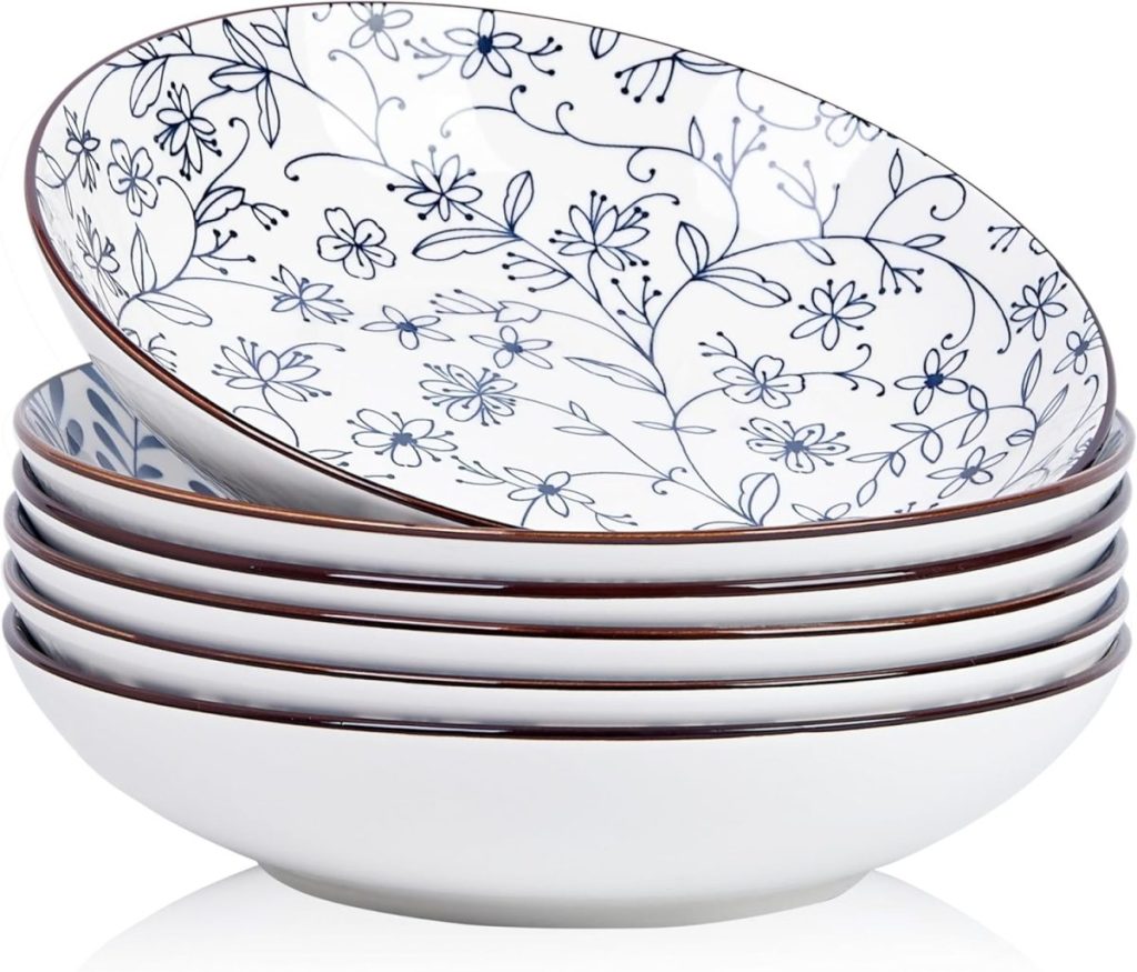 A stack of six white ceramic bowls with a blue floral pattern on the inside and a thin brown rim, perfect for serving fettuccini.