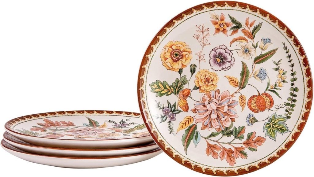 Five floral-patterned Thanksgiving plates with a brown rim, stacked neatly with one standing upright.