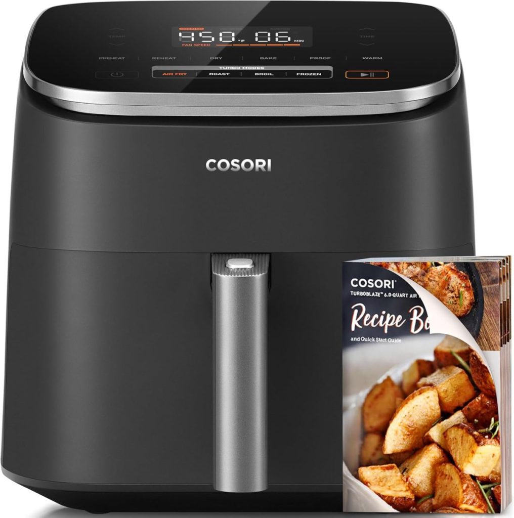 A black Cosori air fryer with a digital display is showcased, available on Amazon Prime. In front of it sits a recipe booklet featuring a dish of roasted potatoes.