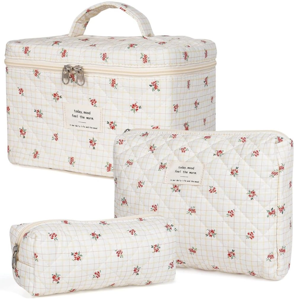 Three cream-colored toiletry bags with red floral patterns and grid lines, featuring zippers and labels, are now available with the convenience of Amazon Prime.