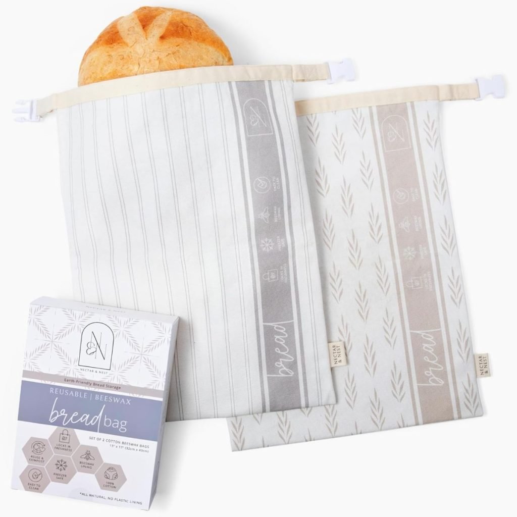 Reusable beeswax bread bags, one holding a loaf, with a patterned design in neutral colors. Packaging displayed in the foreground.