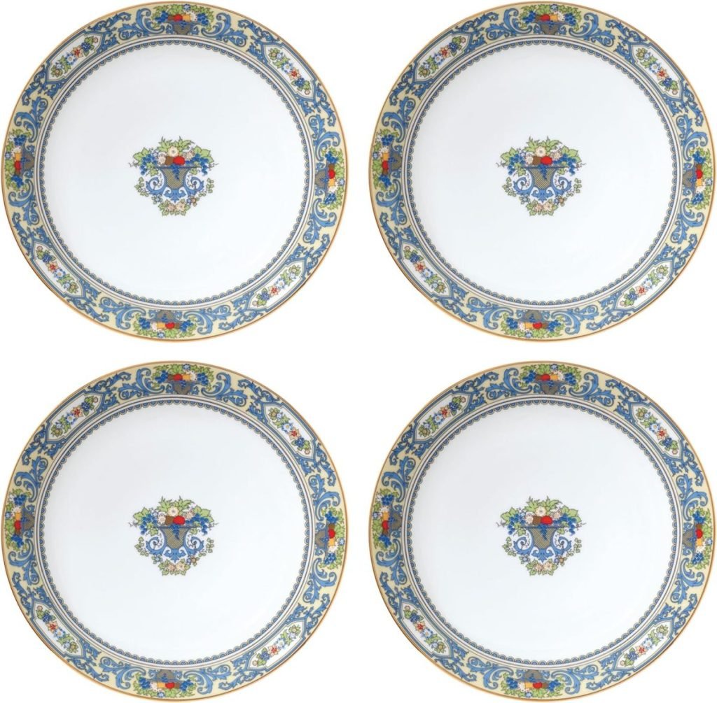 Four decorative white plates, perfect for Thanksgiving, boast blue, yellow, and red floral designs around the edges with a central floral motif.