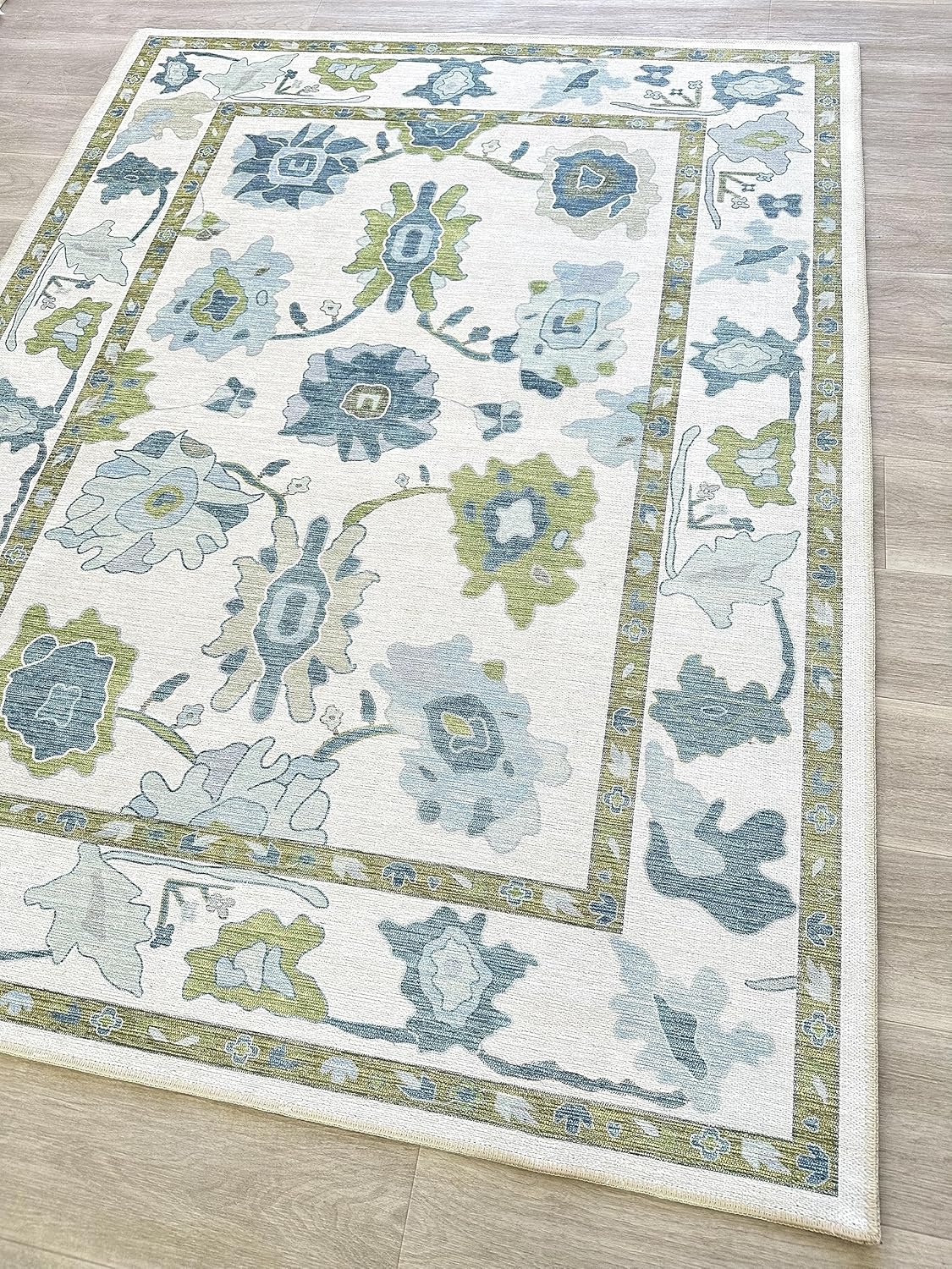 Rectangular Serena and Lily area rug with a cream background featuring blue and green floral patterns, set on a light wood floor.