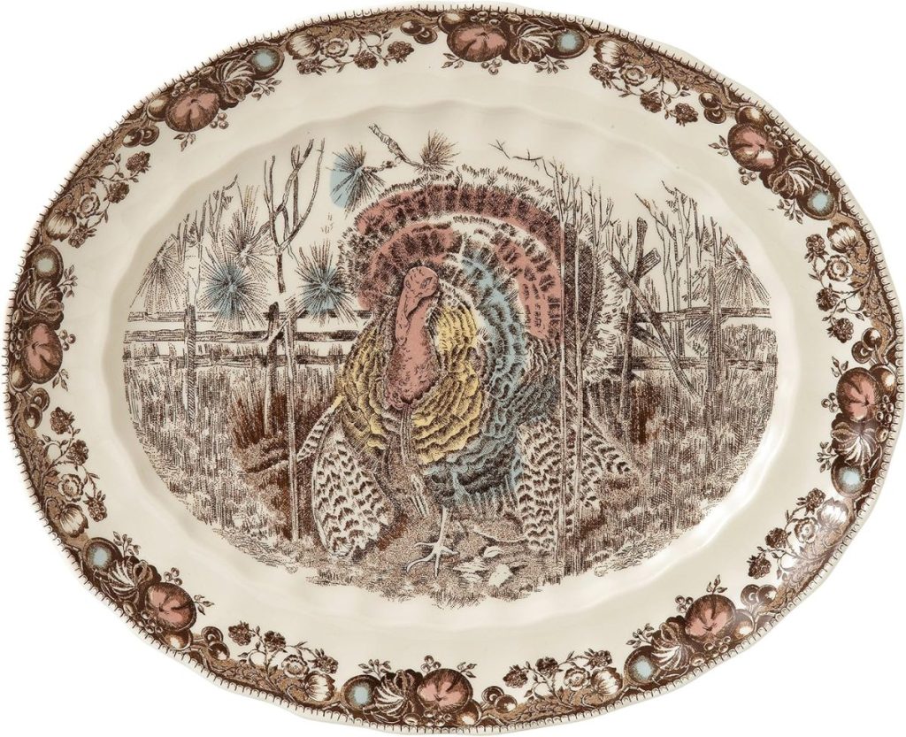 Oval ceramic platter featuring a detailed illustration of a turkey on a rustic background, perfect for serving baked brie with jam, and adorned with a floral and fruit border design.