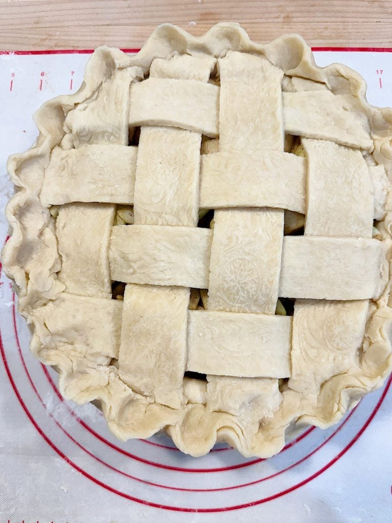 Unbaked pie with a lattice crust rests on a circular baking mat.