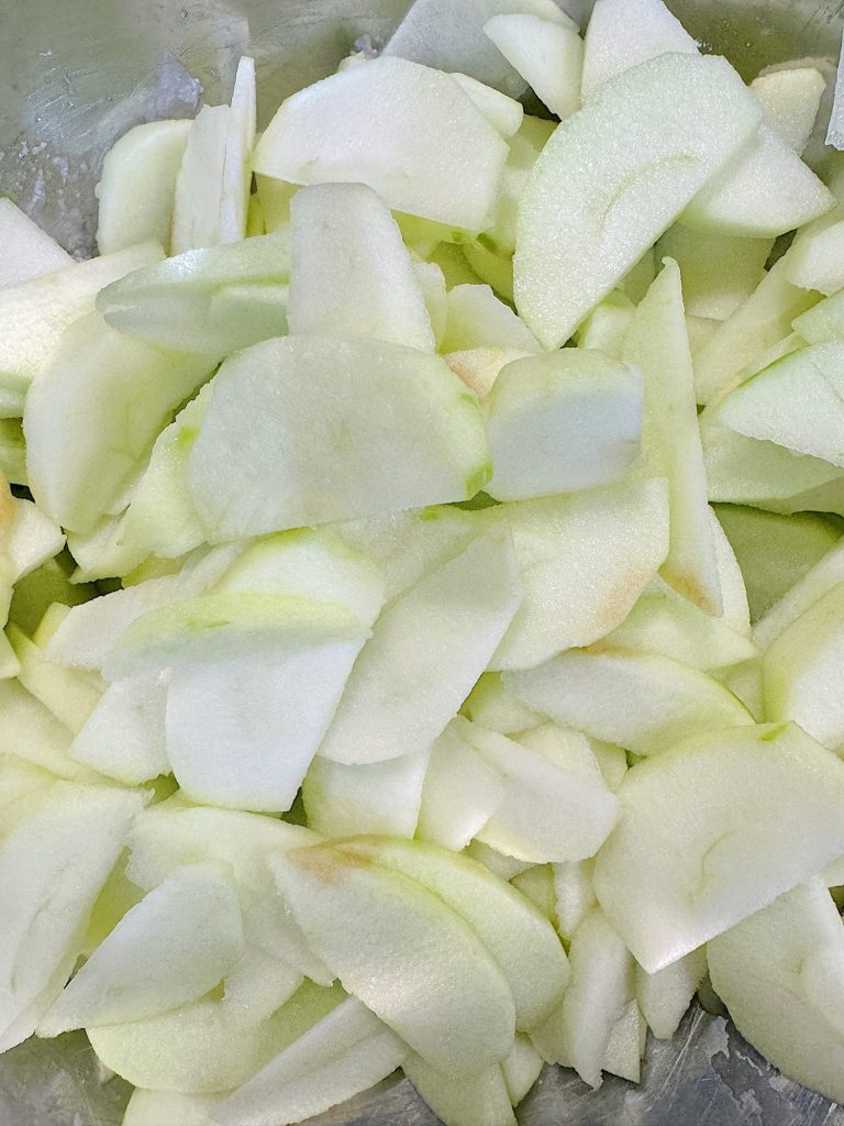 Sliced green apples piled on a surface.