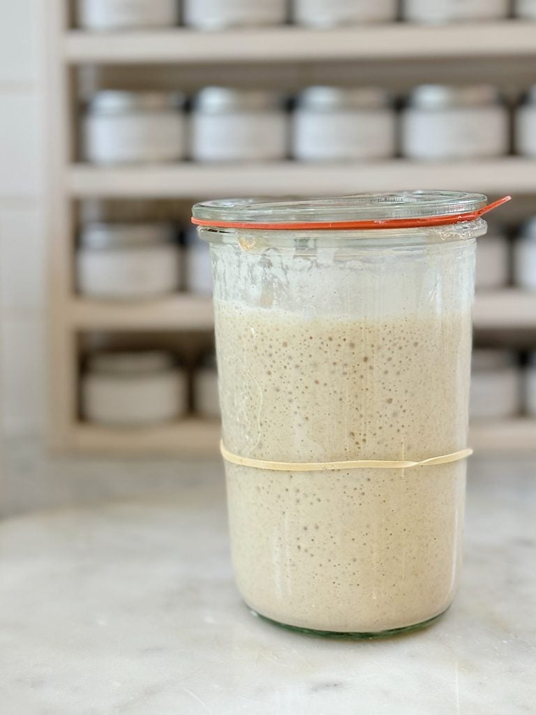 Glass container with sourdough starter and a glass lid..