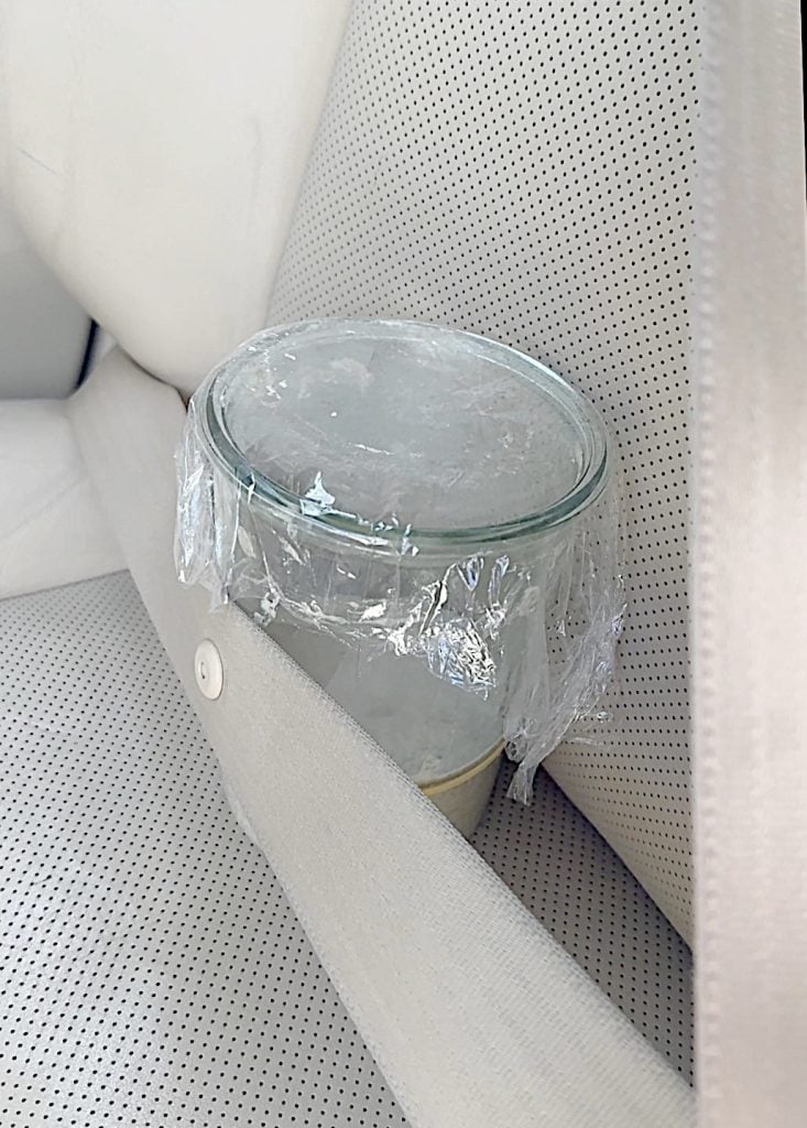 A jar of sourdough starter transported in the front seat of a car with the seat belt securing it's transfer.