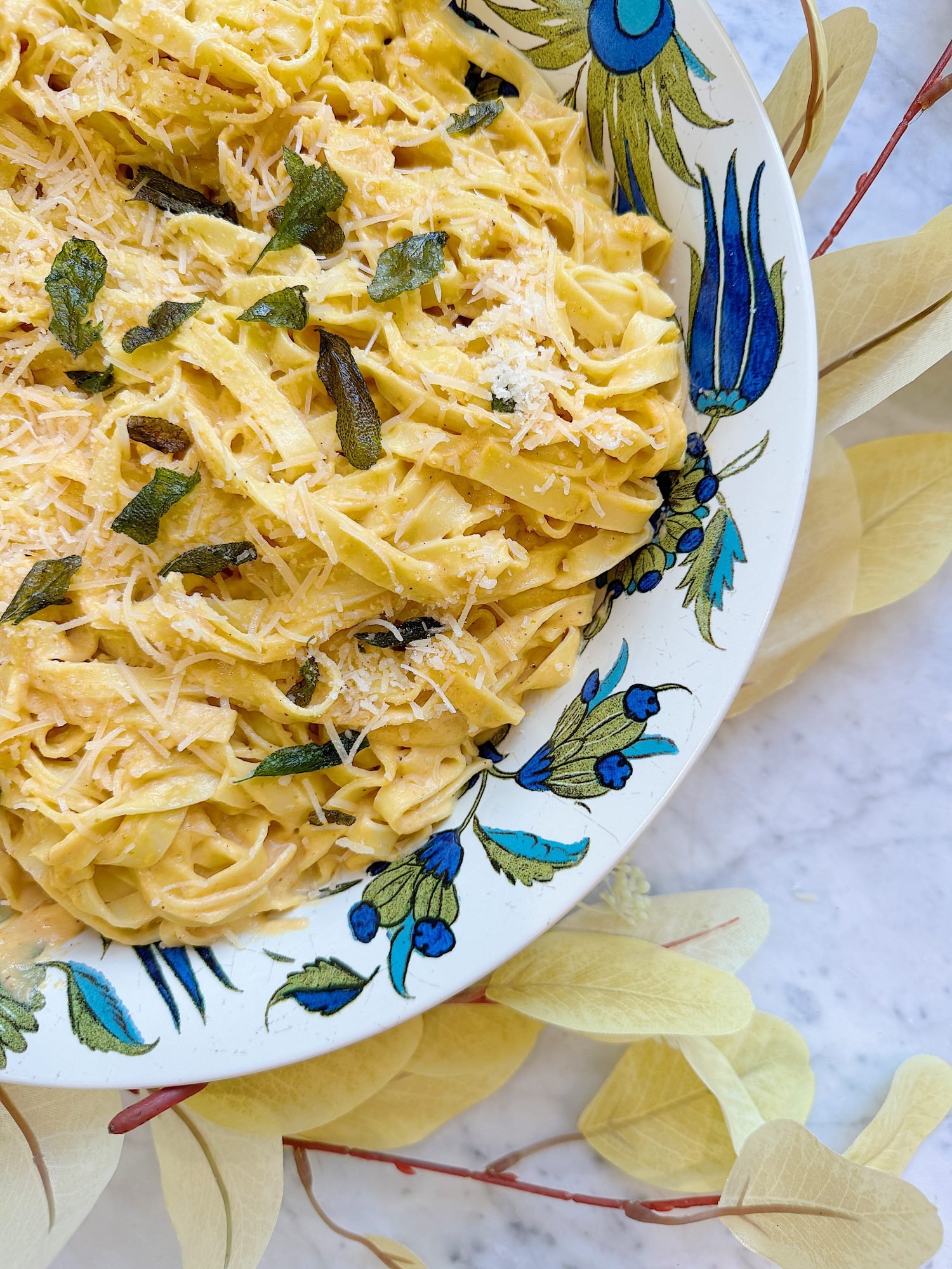 A plate of creamy pasta garnished with grated cheese and herbs, served in a decorative bowl.