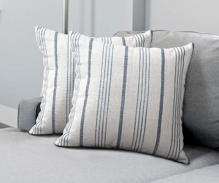 Two white cushions with blue vertical stripes are placed on a light gray sofa.