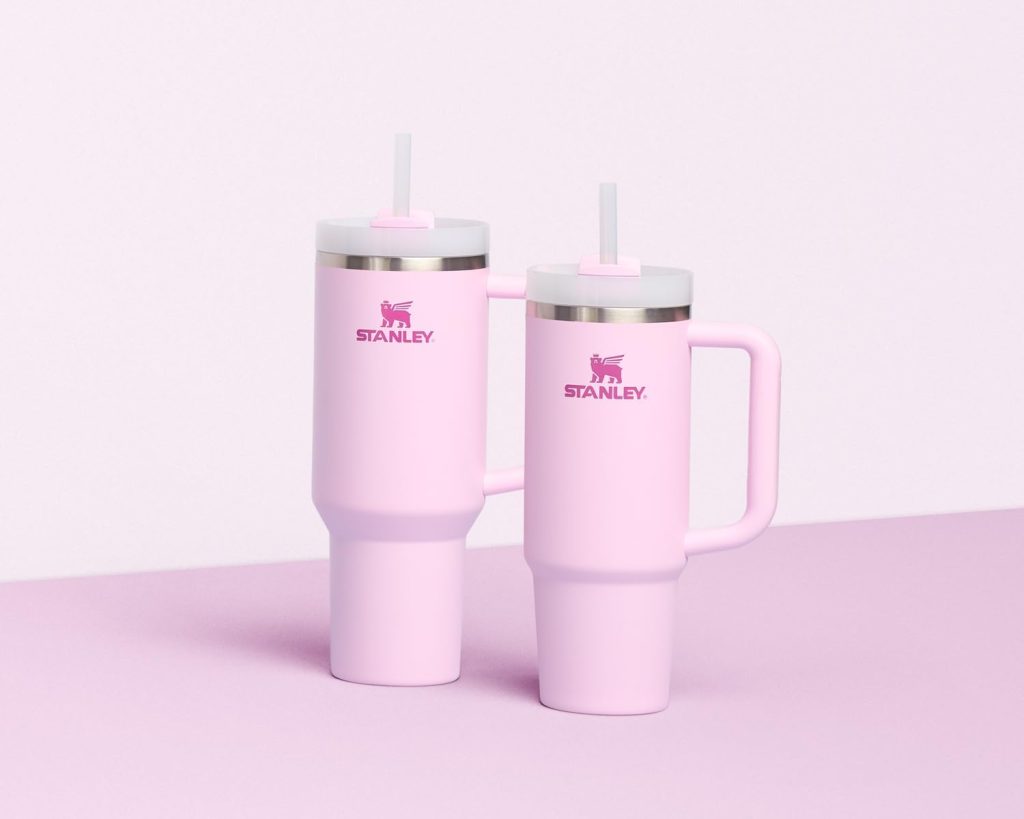 Two pink Stanley tumblers with white lids and straws are positioned side by side on a light pink surface with a pale pink background—perfect for gifting or snagging on Black Friday.