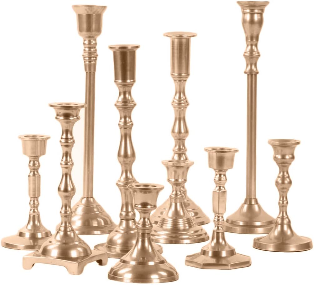 A collection of nine brass candlesticks, reminiscent of Christmas colors with their warm golden hues, are arranged together in varying heights and designs.