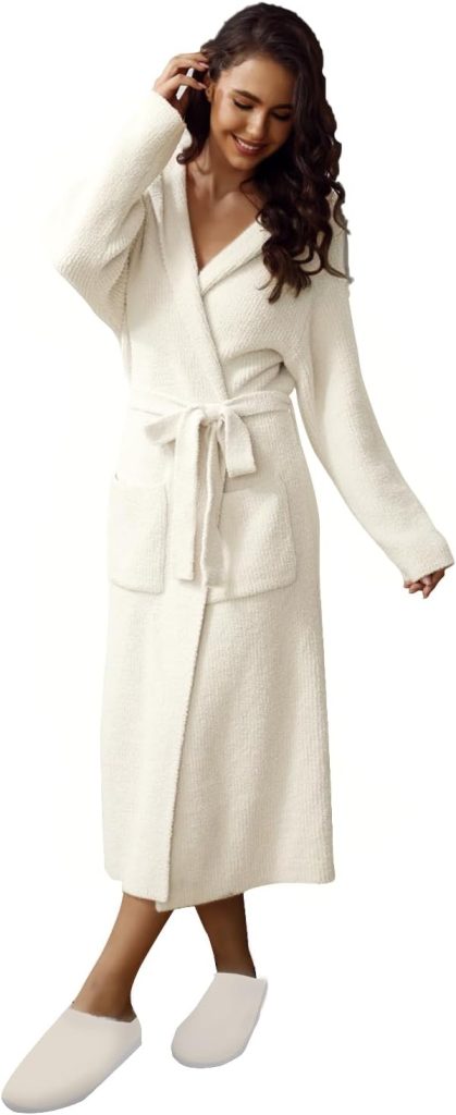 Woman wearing a long, white bathrobe with a belt and front pockets, paired with matching white slippers—perfect for relaxing in style or treating yourself this Black Friday.