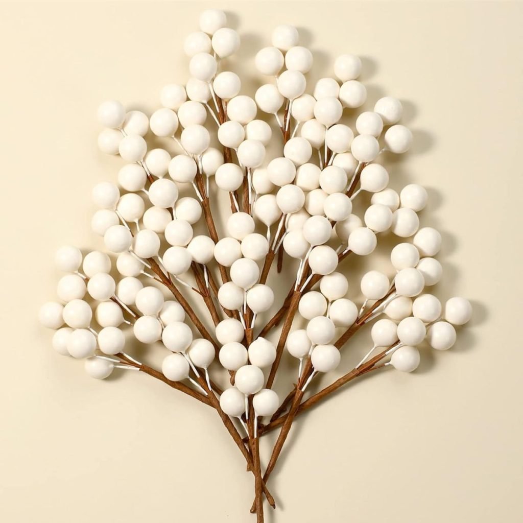 Cluster of white berry-like ornaments on brown stems, arranged against a light background, evoking a touch of Christmas colors.