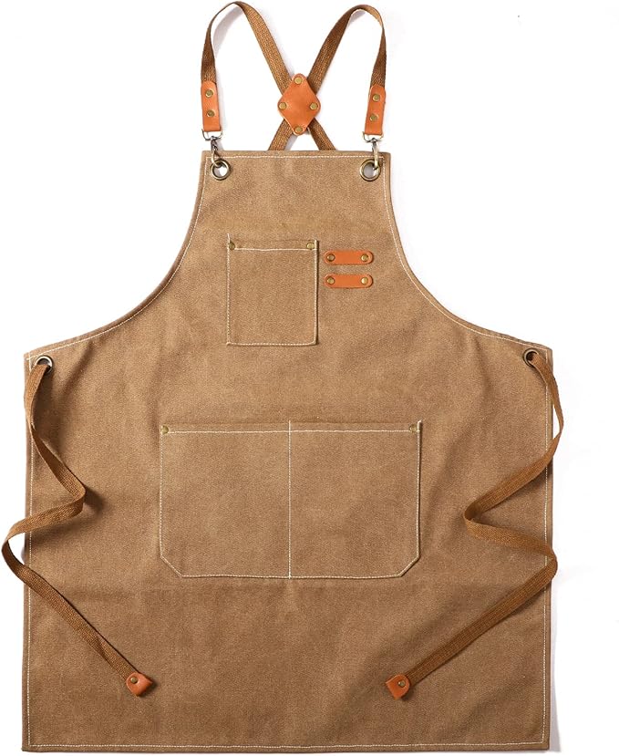 Brown canvas apron with three pockets, adjustable cross-back straps, and leather accents, perfect for crafting a festive Christmas Morning breakfast, laid flat on a white background.
