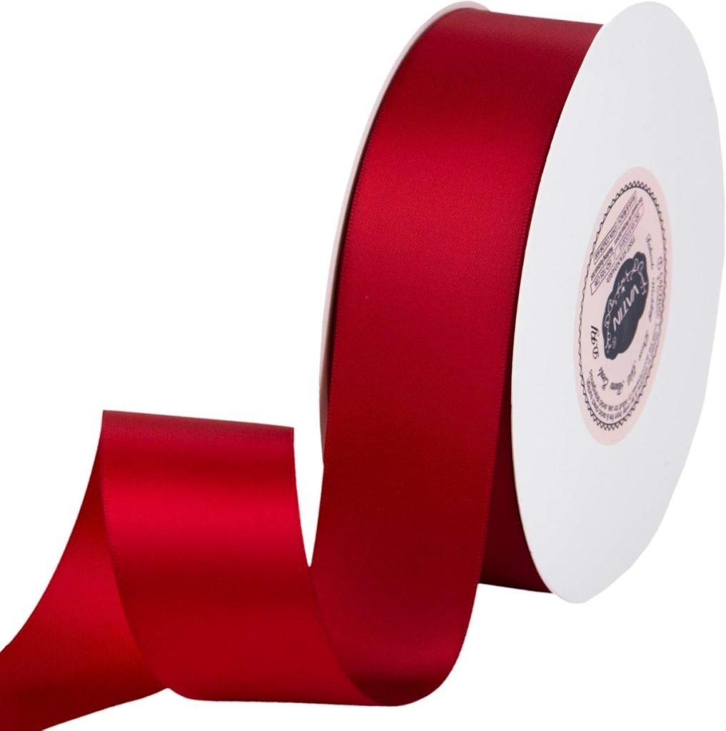 A roll of wide red satin ribbon, perfect for gift wrapping, partially unwound on a white spool.