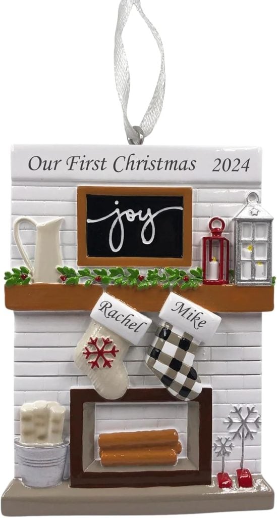 A Christmas ornament featuring a fireplace with stockings labeled "Rachel" and "Mike," with "Our First Christmas 2024" inscribed at the top.