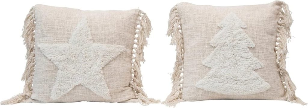 Two beige pillows with textured designs: one adorned with a star and the other featuring a tree, bring a subtle touch of Christmas colors. Tassels elegantly hang from the sides.