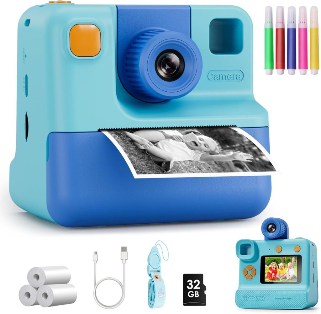 Blue instant camera printing a black-and-white photo—perfect for capturing Christmas Morning memories. Includes markers, photo paper rolls, USB cable, wrist strap, 32GB SD card, and a digital display screen.