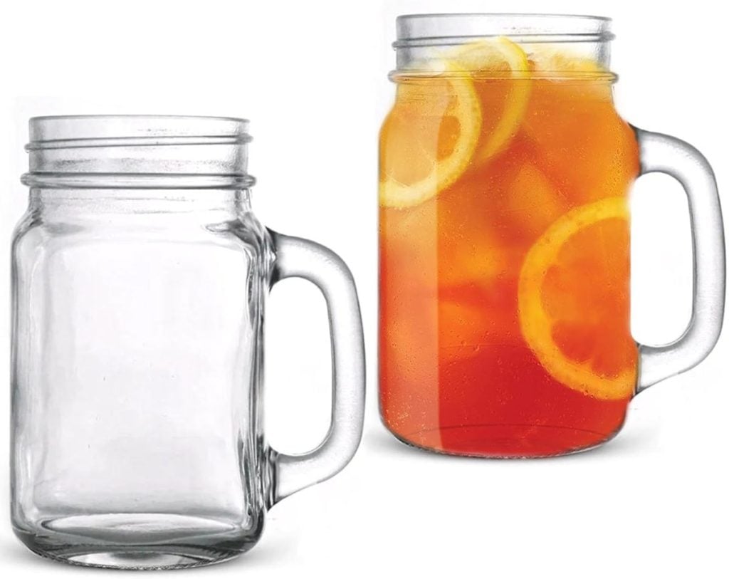 Two mason jar mugs sit side by side; one is empty, and the other is brimming with iced tea and lemon slices. The scene evokes a cozy holiday gathering, reminiscent of a nutcracker Christmas.