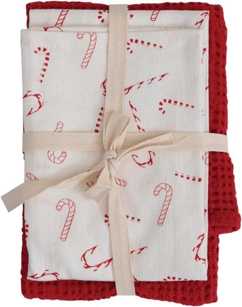 Two folded kitchen towels, one red textured and one white with red candy cane print, tied together with a beige ribbon—perfect for adding a festive touch to your kitchen during the holiday season.
