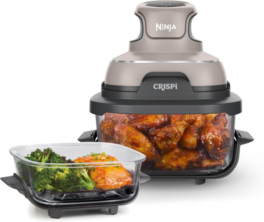 A Ninja CRISPI air fryer with cooked chicken wings inside sits next to a separate container holding broccoli and salmon, ready for a delicious Black Friday meal.