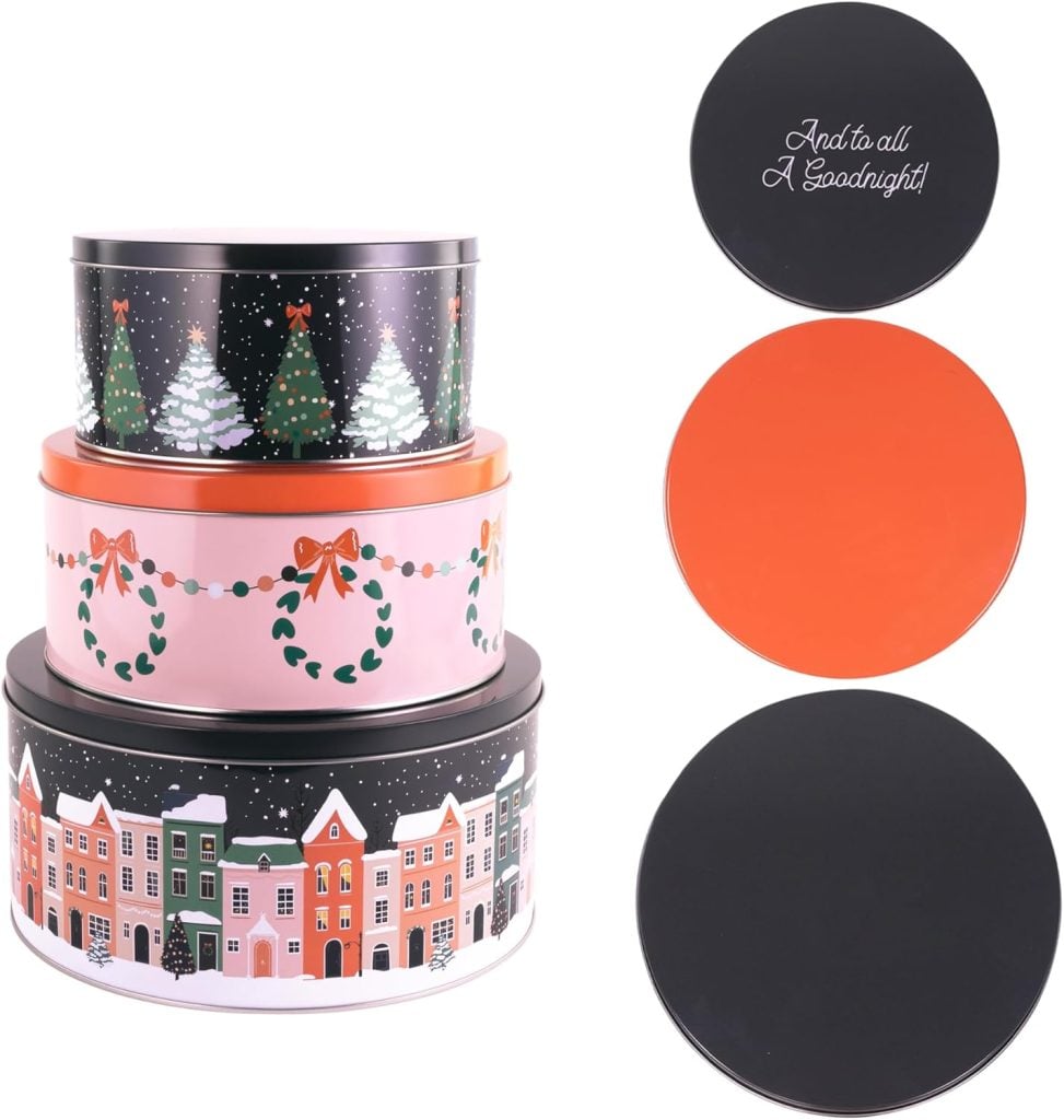 Three decorative holiday-themed tins stacked, each with different designs: snowy trees, wreaths with bows, and a village street. Lids are shown separately, two solid colors and one with text.