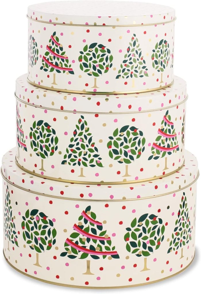 Three stacked round tins decorated with green holiday trees and red, pink, and gold dots.