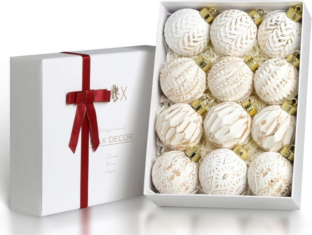 A set of twelve white and gold decorative Christmas ornaments in an open box, showcasing the classic Christmas colors, adorned with a red ribbon.