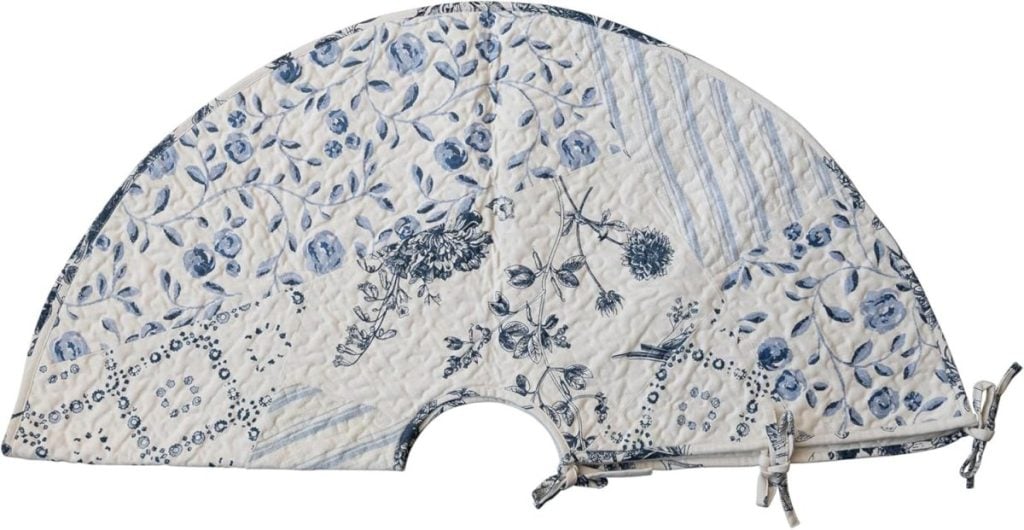 Semi-circular quilted fabric tree skirt with blue floral and geometric patterns on a white background, evoking a Beach Christmas vibe, and featuring ties for fastening.