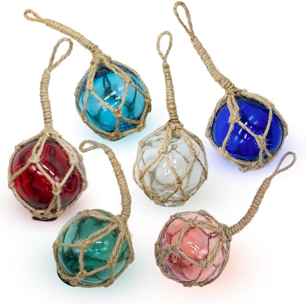 Six glass floats in red, blue, clear, teal, and pink are encased in knotted rope netting, each with a loop for hanging.