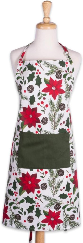 Festive apron adorned with red poinsettias, pinecones, and greenery on a white background, reminiscent of Christmas tree cupcakes. Displayed on a mannequin, it features a dark green front pocket for a charming holiday touch.