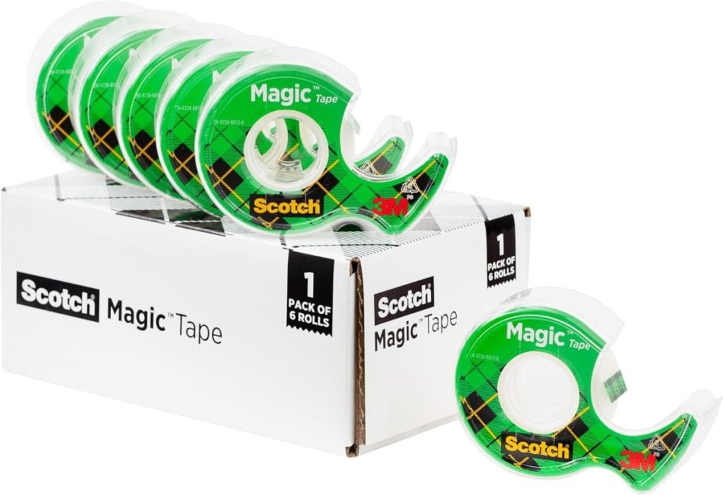 Six rolls of Scotch Magic Tape, perfect for gift wrapping, featuring green plaid design on dispensers, neatly placed on a white box labeled “Scotch Magic Tape.”